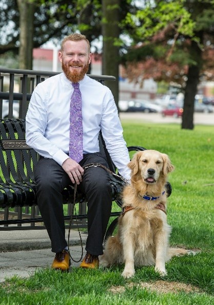 David Locklin sits on a bench next to a golden retriever